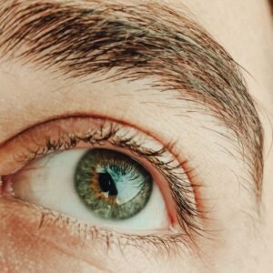 Close-up shot of a hazel eye, highlighting intricate details of the eyelashes and eyebrow.